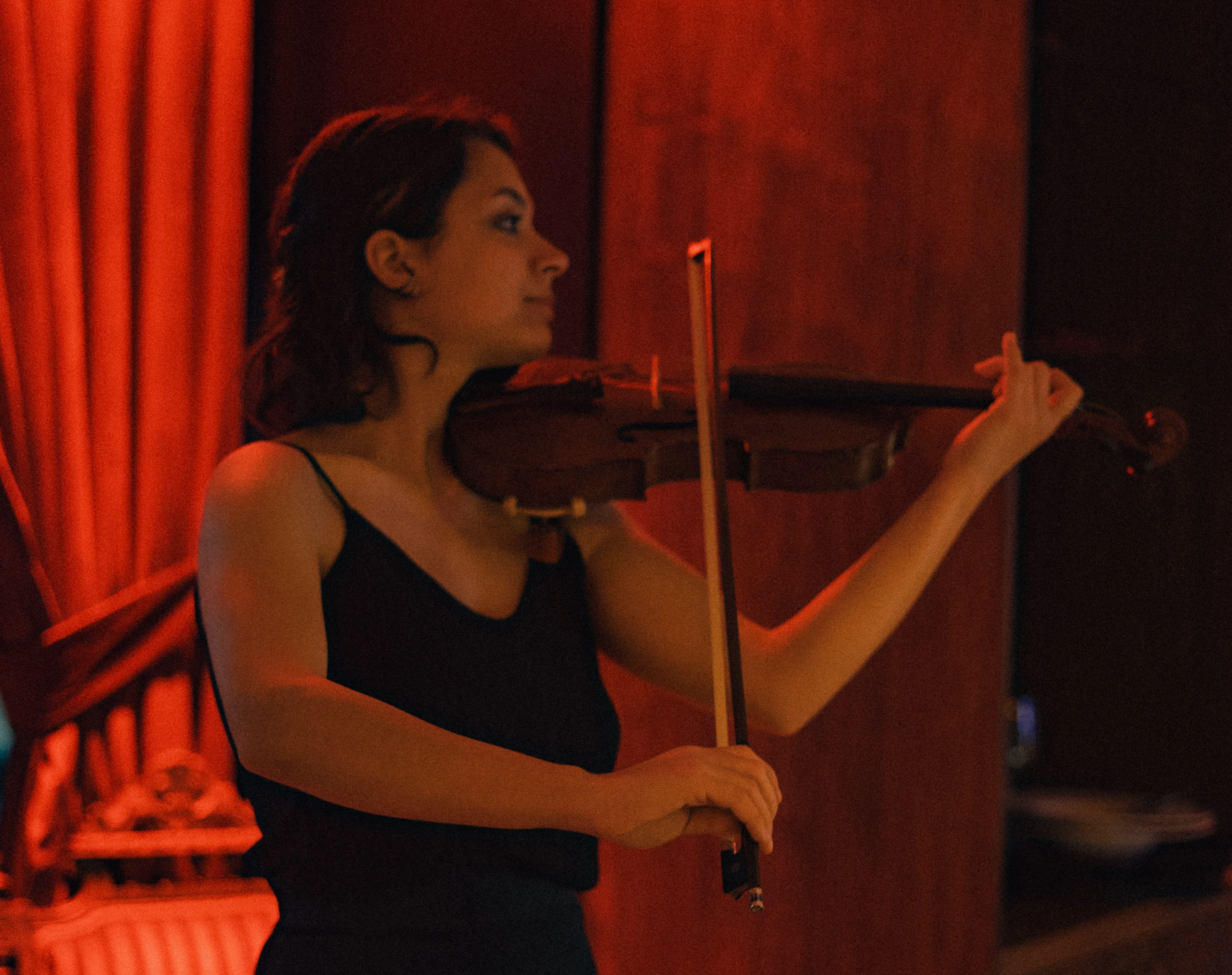 Female violinist performing live music under red stage lighting at Hemdem events evening Istanbul